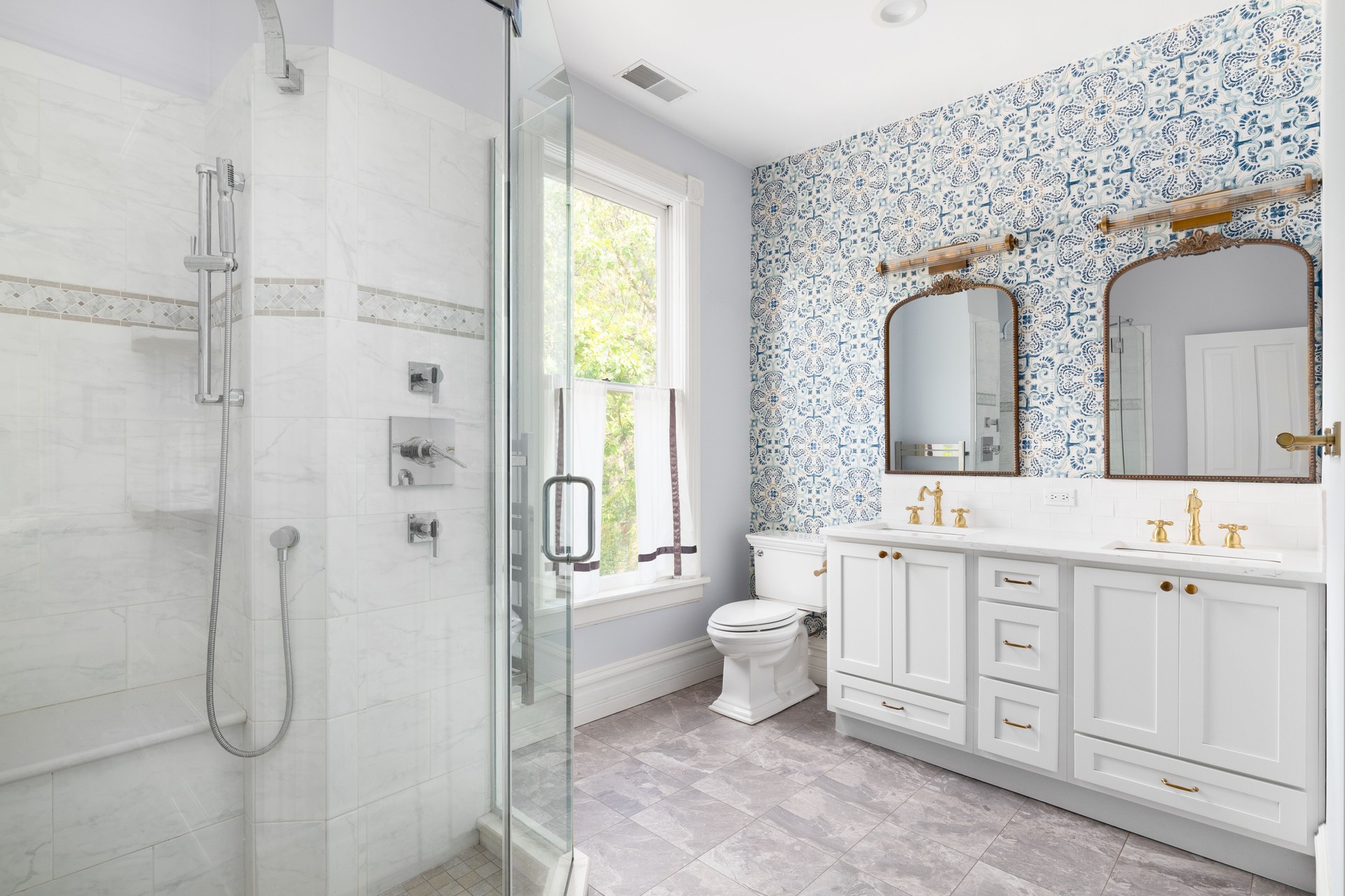 A bathroom with gold faucets and blue wallpaper.